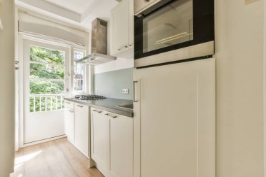 Modern dolap, evdeki geniş ışıklı mutfakta şık bir egzoz kapağının altında.