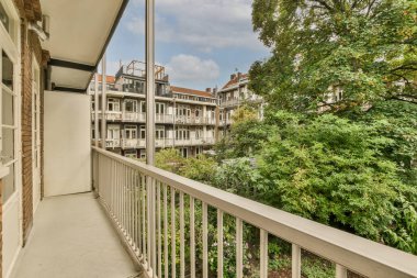 Panoramic view of brick buildings with parking and trees from small balcony