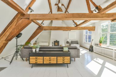 Beyaz tavanlı, çağdaş dairenin geniş odasındaki dinlenme odası ve mutfağın yanındaki sandalyeli ve çiçekli masa.