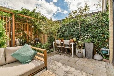 Neat powerful patio with sitting area and small garden near wooden fence