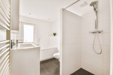 Modern sifon tuvaleti ve seramik lavabo aynanın yanındaki beyaz fayanslı duvarlara ve evdeki küçük tuvaletteki havluya monte edildi.