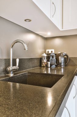 Çağdaş açık mutfak, yemek masası seti ve ferah odada gri kanepe.