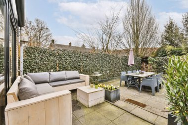 Oturma alanı ve ahşap çitlerin yanındaki küçük bahçesi olan düzgün asfaltlı bir avlu.