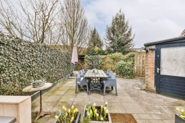 Neat paved patio with sitting area and small garden near wooden fence