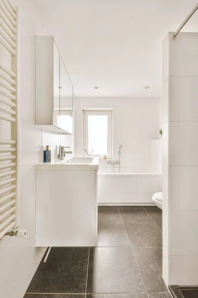 鏡とタオルの近くの白いタイル張りの壁に設置された現代のフラッシュトイレとセラミックシンク自宅の小さなトイレに — ストック写真
