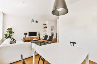 Modern apartmandaki dekorasyonlu ve televizyonlu, rahat koltuğun yanına yerleştirilmiş eski püskü ahşap masa.