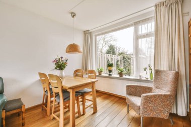 TV 'nin yanındaki koltuklar ve masa, çağdaş apartmandaki geniş odalı yemek alanına karşıdır.