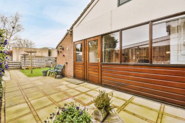 Oturma alanı ve ahşap çitlerin yanındaki küçük bahçesi olan düzgün asfaltlı bir avlu.