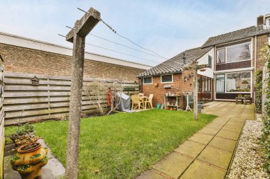 Oturma alanı ve ahşap çitlerin yanındaki küçük bahçesi olan düzgün asfaltlı bir avlu.