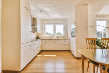 Günümüz minimalist tasarımı. Hafif stüdyo dairesinin ahşap masası ve oturma odası ile beyaz duvarları ve parke zemini arasında yemek masası ve sandalyeleri var.