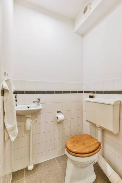 带有水池和墙壁的狭窄卫生间的内部悬挂着带有白色墙壁和有格子地板的厕所 — 图库照片