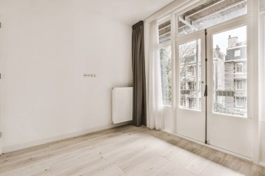 Modern dolap ve klasik sandık, beyaz duvarları ve ahşap zemini olan geniş bir odada, kapıların ve hasır sepetin yanına yerleştirildi.