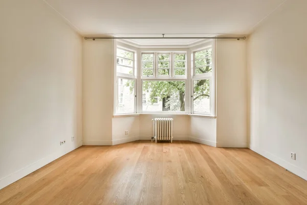 Interior of empty white room with windows with parquet and radiator
