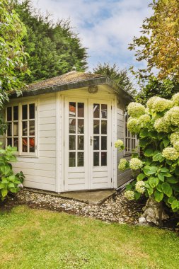 Oturma alanı ve ahşap çitlerin yanındaki küçük bahçesi olan düzgün asfaltlı bir avlu.