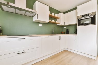 Minimalist tarzı beyaz mobilyalı, lavabolu ve sobalı bir ev mutfağı.