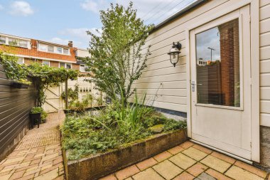 Oturma alanı ve ahşap çitlerin yanındaki küçük bahçesi olan düzgün asfaltlı bir avlu.