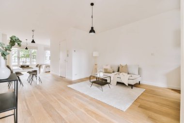 Modern apartmandaki dekorasyonlu ve televizyonlu, rahat koltuğun yanına yerleştirilmiş eski püskü ahşap masa.