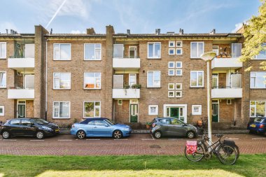 Arabaları, ağaçları ve fenerleri olan boş bir kaldırımdan panorama manzaralı evler.
