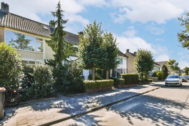 Panorama view of brick houses from an empty sidewalk street with trees and lanterns