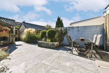 Oturma alanı ve ahşap çitlerin yanındaki küçük bahçesi olan düzgün asfaltlı bir avlu.