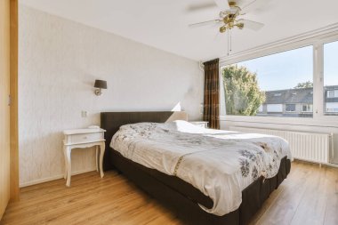 Yatak odasının iç tasarımı, yatak odası ve ahşap gardırop modern dairenin penceresinin kenarına yerleştirilmiş.