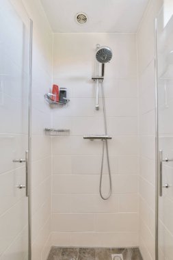 Sinks with mirrors and shower box with glass door in modern bathroom with white tiled walls