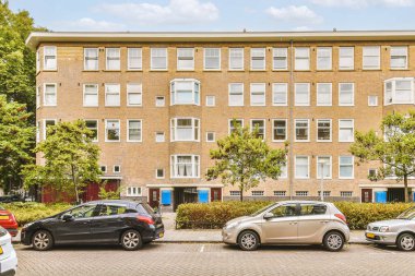 Arabaları, ağaçları ve fenerleri olan boş bir kaldırımdan panorama manzaralı evler.