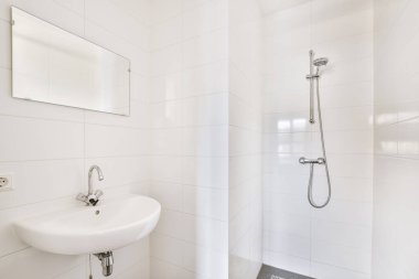 Aynalı lavabo ve temiz duş kutusu modern banyoda cam kapılı beyaz fayanslı duvarları var.