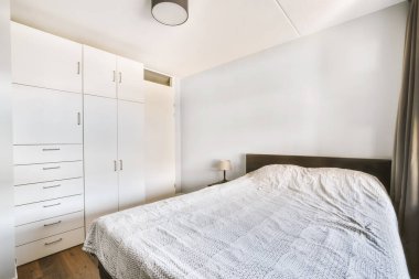 Yatak odasının iç tasarımı, yatak odası ve ahşap gardırop modern dairenin penceresinin kenarına yerleştirilmiş.