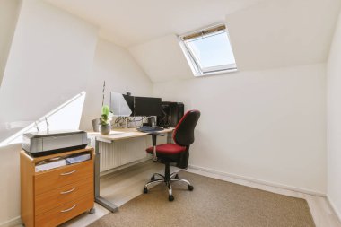 Modern apartmandaki hafif iş yerinde bilgisayar monitörleri ve beyaz tahtanın olduğu masanın yanına konforlu sandalye