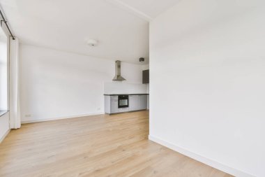 Pencereleri ve ahşap parke zemini olan boş beyaz mutfağın içi.