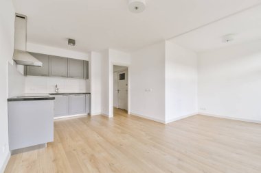 Pencereleri ve ahşap parke zemini olan boş beyaz mutfağın içi.