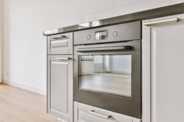 Pencereleri ve ahşap parke zemini olan boş beyaz mutfağın içi.