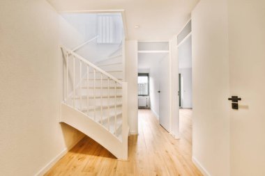 Minimalist iç tasarımı olan modern lüks dairenin ikinci katına çıkan ahşap merdivenli beyaz koridor.