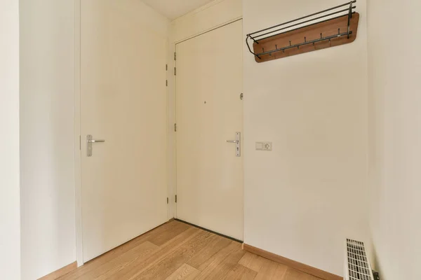 白い壁とドアを持つ狭い廊下は 現代のアパートの窓や寄木細工の床と広々とした部屋につながります — ストック写真