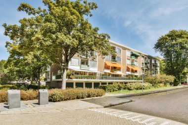Arabaları, ağaçları ve fenerleri olan boş bir kaldırımdan panorama manzaralı evler.