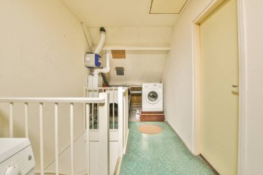 Boruları, ölçüm cihazları ve çamaşır makinesi olan bir apartmanın tavan arası koridoru..