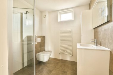 Evdeki modern tuvalette asılı duran banyo musluğu ile duvar arasındaki cam bölme.