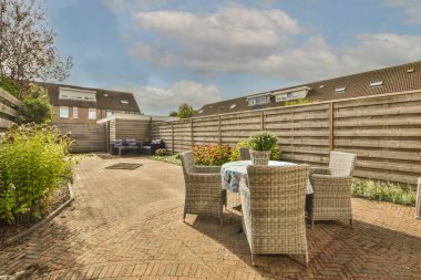 Neat powerful patio with sitting area and small garden near wooden fence