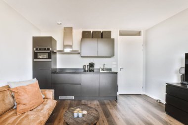 Çağdaş açık mutfak, yemek masası seti ve ferah odada gri kanepe.