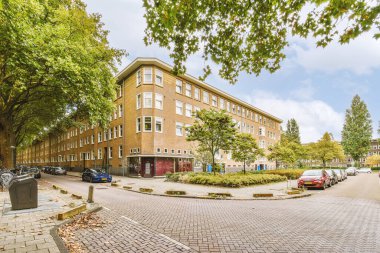Arabaları, ağaçları ve fenerleri olan boş bir kaldırımdan panorama manzaralı evler.