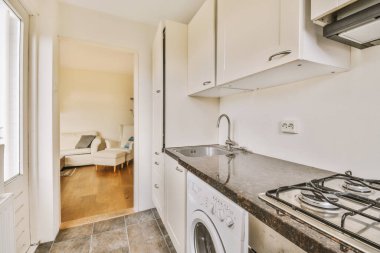 Minimalist tarzı beyaz mobilyalı, lavabolu ve sobalı bir ev mutfağı.