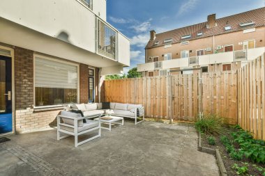 Neat powerful patio with sitting area and small garden near wooden fence