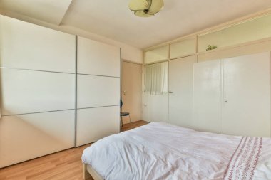 Rahat yatak ve lamba, modern apartmanın penceresinde kırmızı duvarları ve gri perdeleri olan rahat bir yatak odasına yerleştirilmiş.