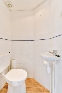 Lavabolu ve duvarlı, beyaz duvarlı ve kareli tuvaletli dar bir tuvalet.