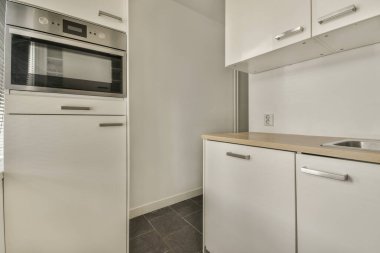 Modern ev mutfağı iç tasarımı beyaz dolaplar, dolaplar ve çelik kapüşon ile çağdaş apartmanda.