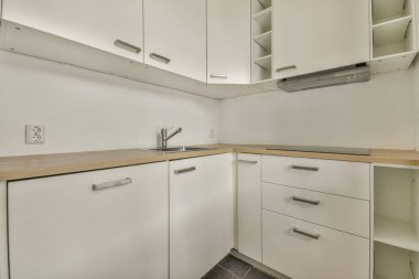 Modern ev mutfağı iç tasarımı beyaz dolaplar, dolaplar ve çelik kapüşon ile çağdaş apartmanda.