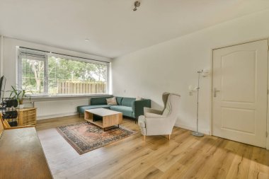 Modern apartman dairesinde, rahat kanepenin yanındaki tahta masa, televizyon, piyano ve gitarlarla donatılmış.