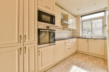 Çağdaş dairenin geniş odasındaki dinlenme odası ve mutfağın yakınındaki sandalyeli ve çiçekli masa.