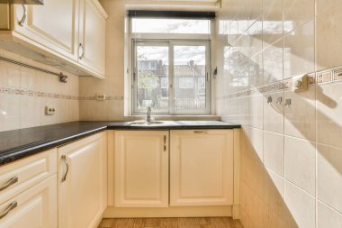 Çağdaş dairenin geniş odasındaki dinlenme odası ve mutfağın yakınındaki sandalyeli ve çiçekli masa.